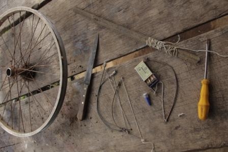 Foto com uma mesa de madeira, em cima várias ferramentas e peças.