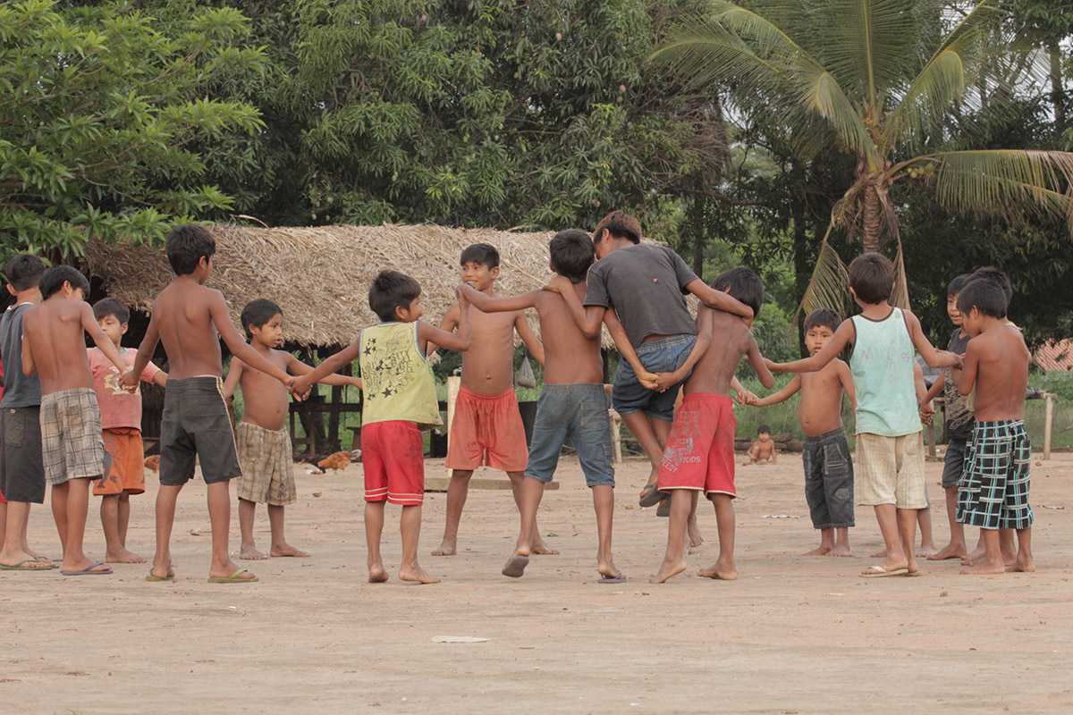 Foto composta por várias crianças em uma roda, de mãos dadas elas brincam.