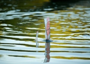 Foto de um barco a vela de brinquedo em um lago.