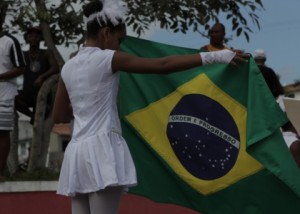 Foto de uma garota estendendo uma bandeira do Brasil.
