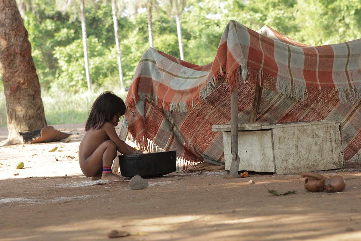Foto de uma garota, abaixada ela mexe em uma bacia.