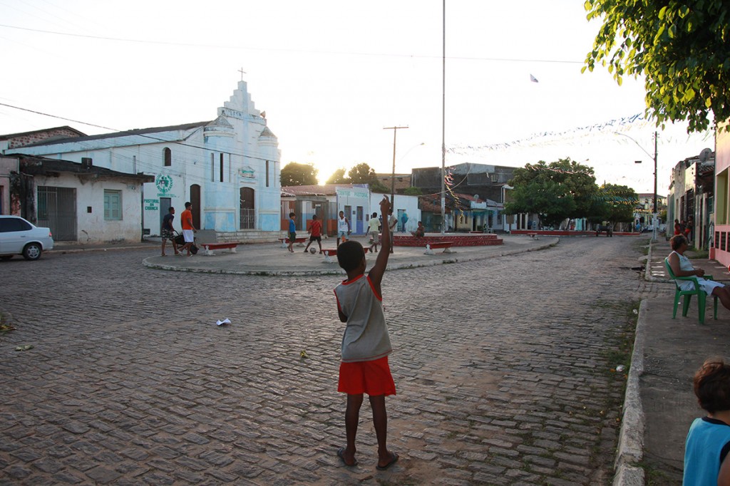 Foto de um garoto em uma praça empinando uma pipa.