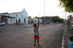 Foto de um garoto em uma praça empinando uma pipa.