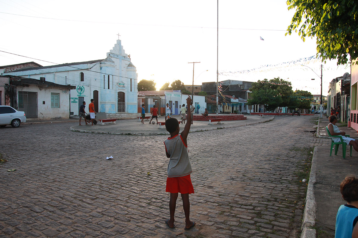 Foto de um garoto em uma praça empinando uma pipa.