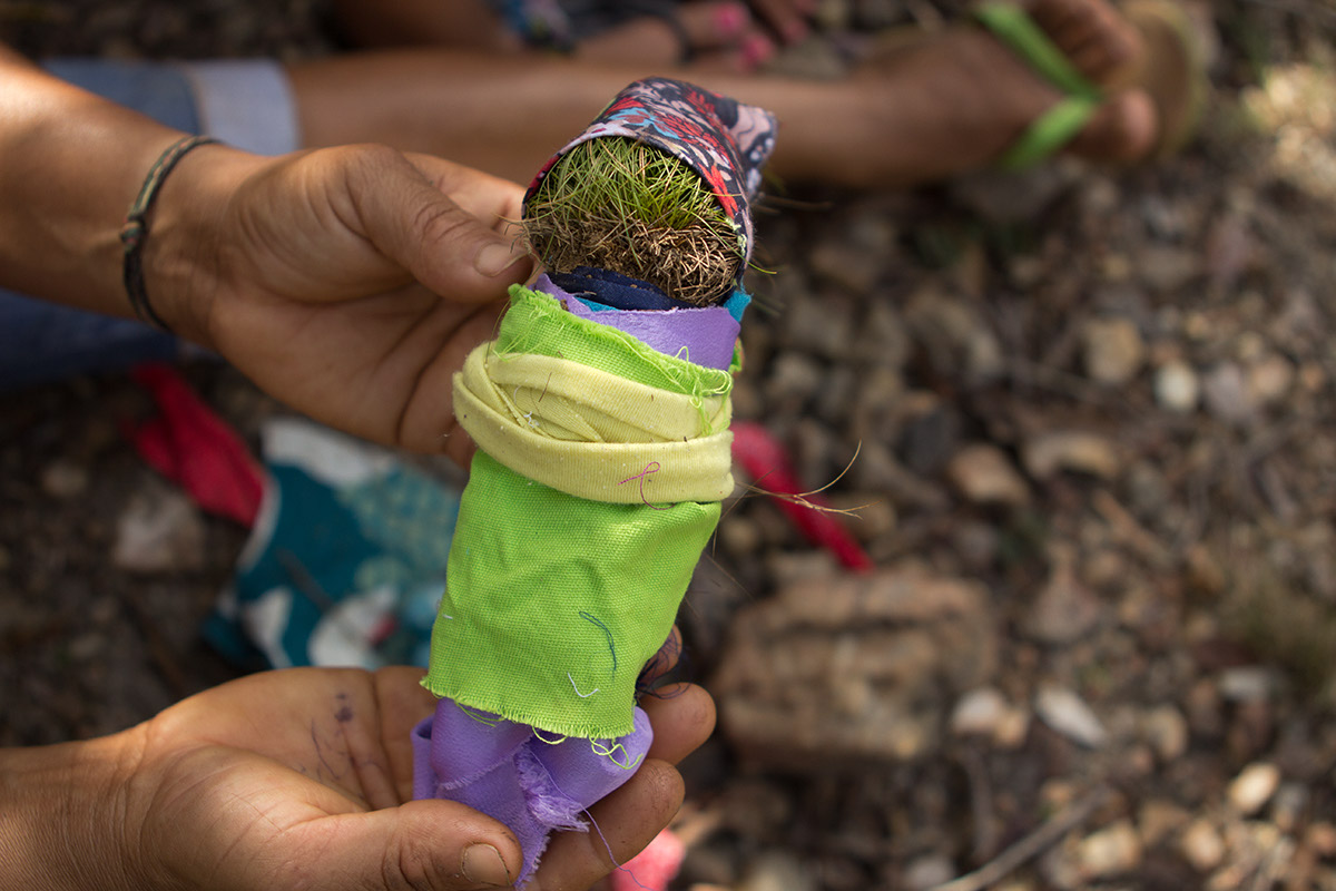 Foto ilustrando uma pessoa segurando uma boneca feita de terra enrolada em panos.