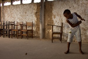 Foto com um garoto brincando de peão, onde logo após ter arremessado um peão, o garoto puxa a corda.