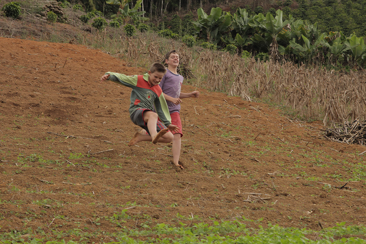 Foto de dois garotos correndo, eles descem um morro.