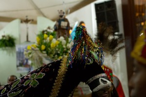 Foto de um bumba meu boi, ao fundo uma imagem de um santo.