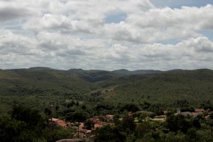 Foto ilustrando um vale com várias casas no centro do vale, ao fundo várias montanhas.