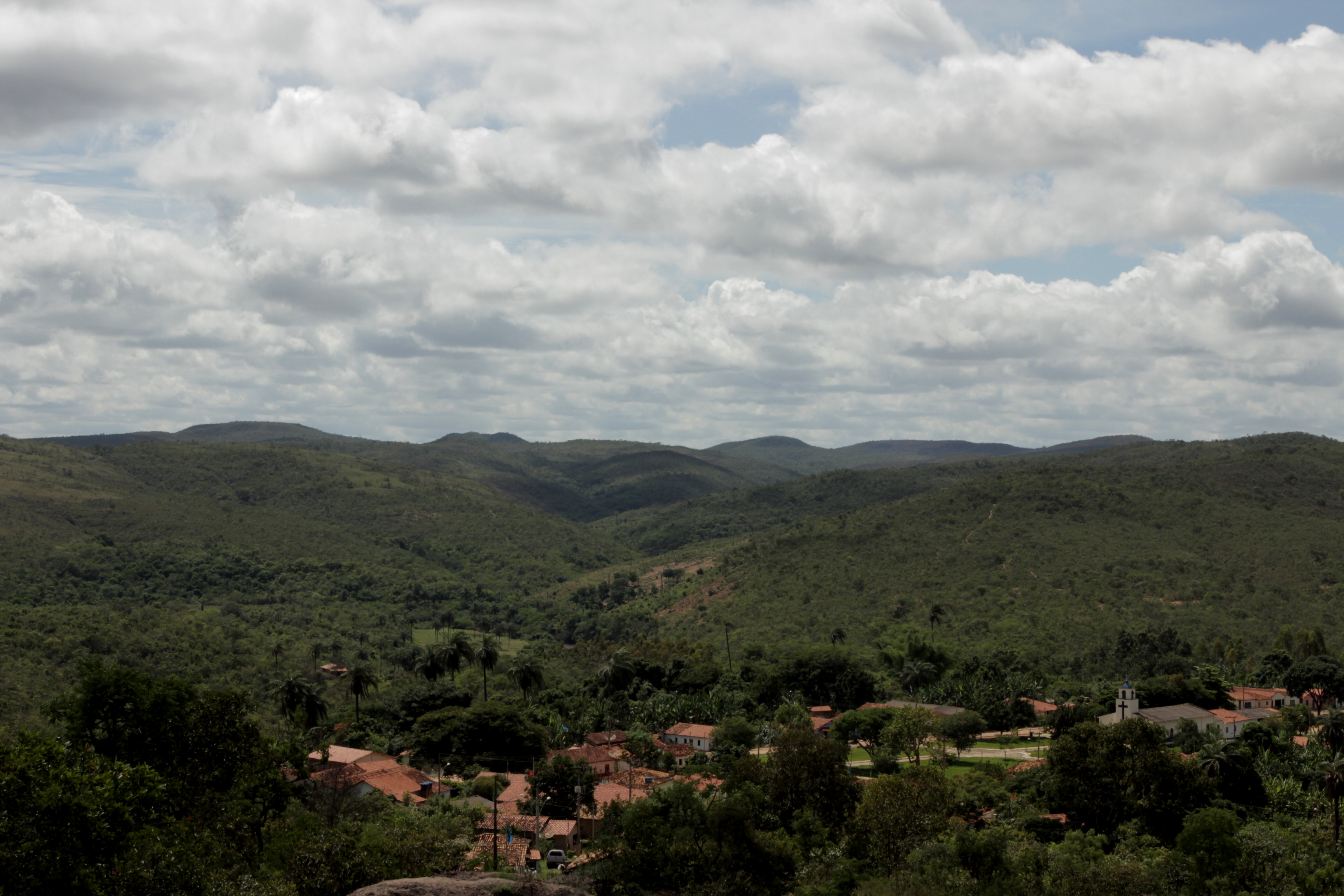 Foto ilustrando um vale com várias casas no centro do vale, ao fundo várias montanhas.