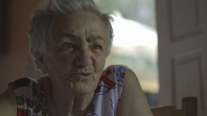 Foto de uma senhora de cabelos grisalhos falando.