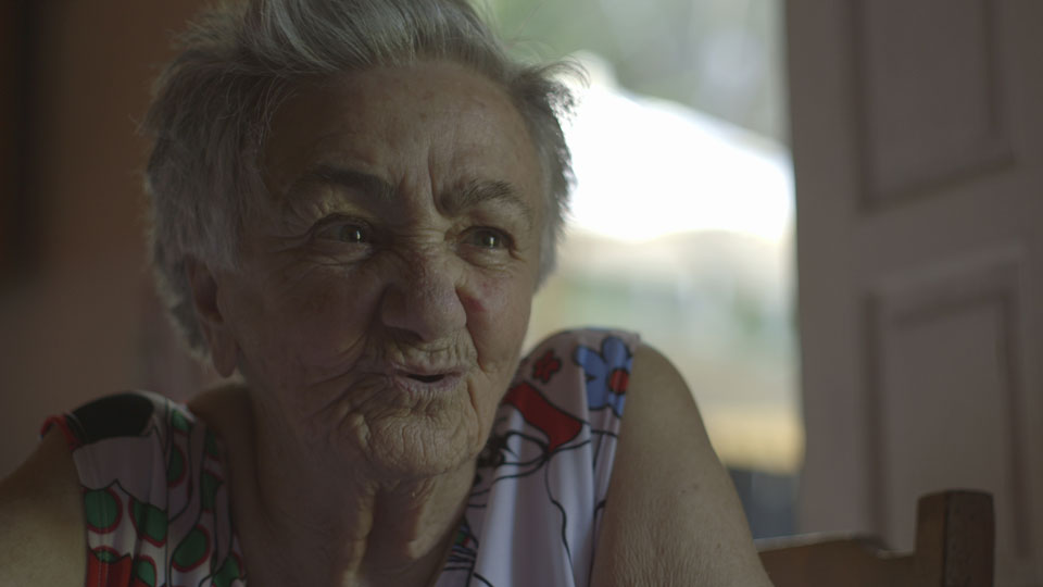 Foto de uma senhora de cabelos grisalhos falando.