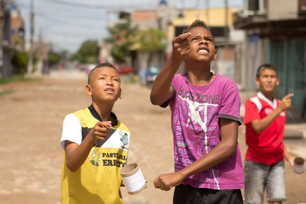 Foto com Três garotos soltando pipa.