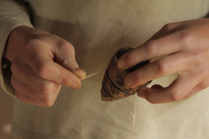 Foto de uma pessoa dando corda em um pião de madeira.