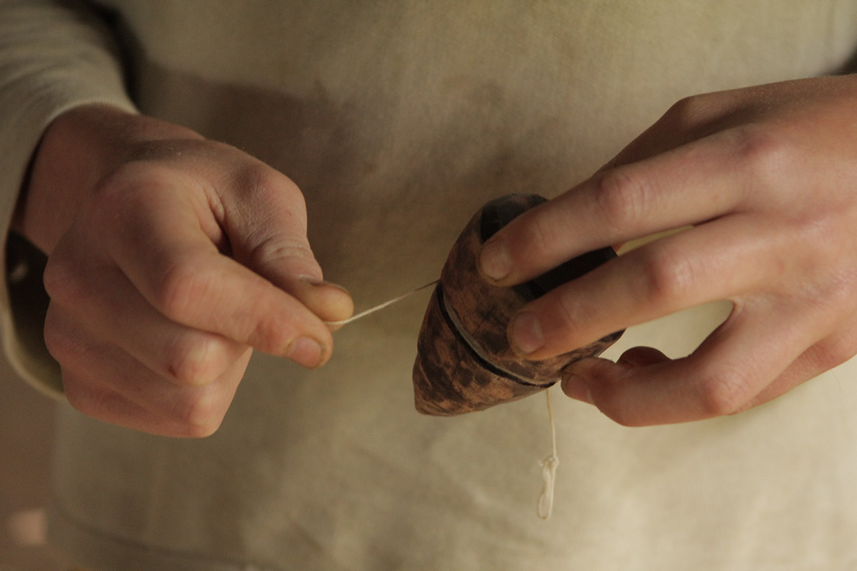Foto de uma pessoa dando corda em um pião de madeira.