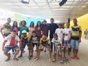 Foto ilustra várias pessoas, cinco garotos estão abaixadas, de traz deles três crianças estão em pé junto com três homens e quatro mulheres.