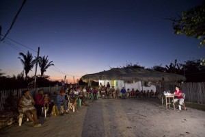 Foto composta por moradores, em um canto uma pessoa manuseia um retroprojetor, os moradores a observam.