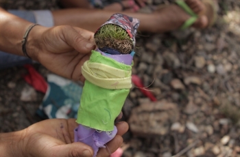 Foto de uma boneca feita de panos multicoloridos e terra, uma pessoa segura a boneca.