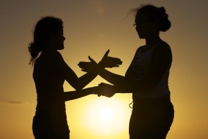 Foto de silhueta de duas meninas brincando de adoleta ao pôr do sol.