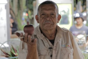 Foto de um senhor segurando um peão enquanto gira em sua mão direita.