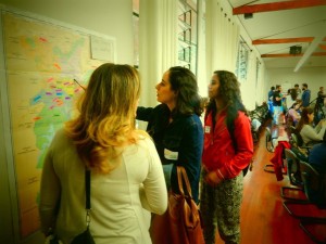 Foto com três mulheres uma esta apontando para um mapa, as outras duas estão observando este mapa.