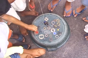 Foto composta por várias crianças em volta de uma bacia virada ao contrário, em cima da bacia tem várias engrenagens e peças.