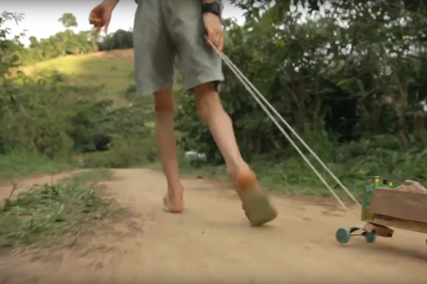 Foto de um garoto correndo enquanto puxa um caminhão cheio de pedras em sua carreta com dois barbante.