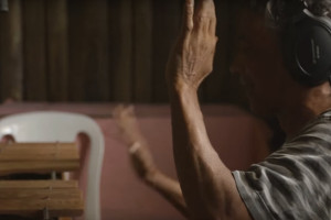 Foto de um home com fones de ouvido escuta musica com as mão levantadas.