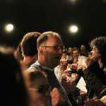 Foto de inúmeras pessoas de mãos dadas em um evento.