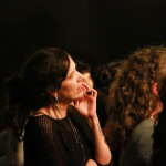 Foto de uma mulher assistindo uma palestra prestando atenção fixamente ao palco.