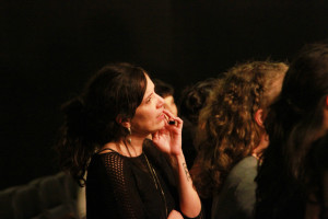 Foto de uma mulher assistindo uma palestra prestando atenção fixamente ao palco.