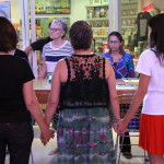 Foto com inúmeras mulheres de mãos dadas formando um circulo .