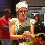 Imagem de uma mulher de avental e roupas floridas com algo em mãos