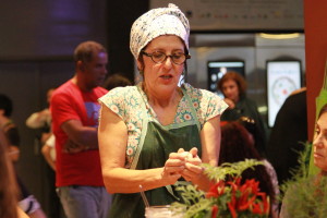 Imagem de uma mulher de avental e roupas floridas com algo em mãos