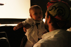 Foto de um homem erguendo um bebê.