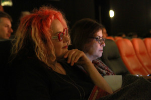 Foto ilustrando interação entre pessoas , onde á duas mulheres ao centro da foto assistindo uma palestra.