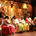 Foto ilustrando um diálogo entre pessoas ,composta de quatro mulheres e dois homens onde a mulher á esquerda tem um microfone á mão.