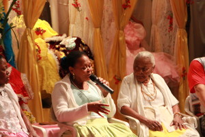 Foto ilustrando um diálogo entre pessoas , onde há duas mulheres negras , a mulher á direita possui um microfone á mão.