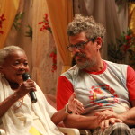 Imagem ilustrando um diálogo entre duas pessoas, uma senhora negra á esquerda com um microfone na mão e um homem á direita .