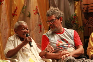 Imagem ilustrando um diálogo entre duas pessoas, uma senhora negra á esquerda com um microfone na mão e um homem á direita .