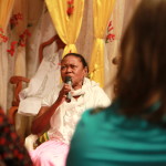 Imagem ilustrando um diálogo onde há uma mulher negra com um microfone falando a um grupo de pessoas.