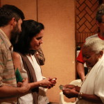 Imagem ilustrando um diálogo entre pessoas , onde há um homem e uma mulher á esquerda e uma senhora a direita lendo algo em um cartão com um outro homem ao fundo.