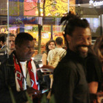 Foto ilustrando interação entre pessoas , onde á um homem negro ao centro sorrindo para a câmera.