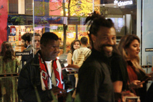 Foto ilustrando interação entre pessoas , onde á um homem negro ao centro sorrindo para a câmera.