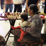 Foto onde á uma mulher sentada com uma criança ao seu colo.