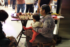 Foto onde á uma mulher sentada com uma criança ao seu colo.