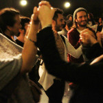 Foto de um grupo de pessoas de mãos dadas em que todos estão felizes prestigiando o evento.