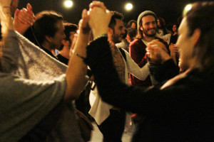 Foto de um grupo de pessoas de mãos dadas em que todos estão felizes prestigiando o evento.