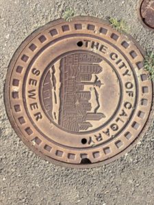 Imagem de uma tampa de um bueiro, nele há uma estampa da cidade de Calgary.